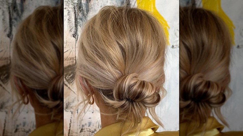 A woman with blond hair in a messy, low bun