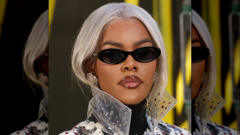 Teyana Taylor posing with gray hair at a Chanel fashion show during Paris Fashion Week while wearing dark shades