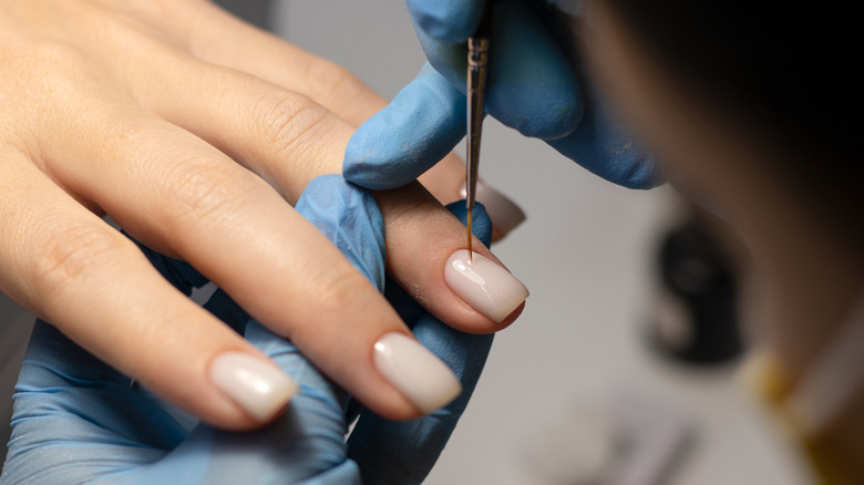 Hand with nude nails getting a manicure