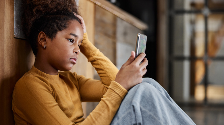 Teen girl sad looking at phone