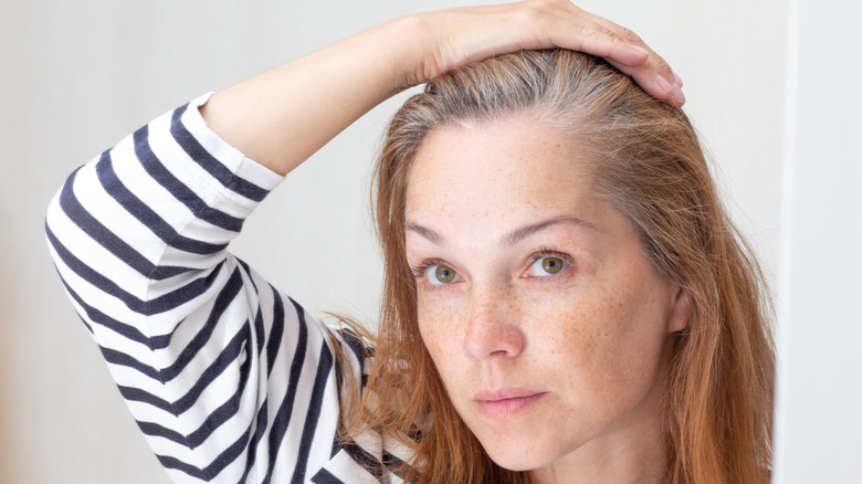 A woman looking at dark hair with silver gray roots