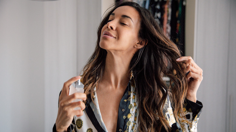 A woman applying body mist to her hair