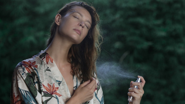 Woman spraying body mist outdoors