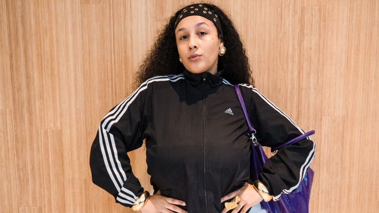 A woman in an Adidas jacket with gold jewelry