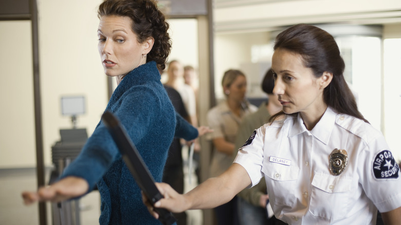 woman being scanned by TSA agent