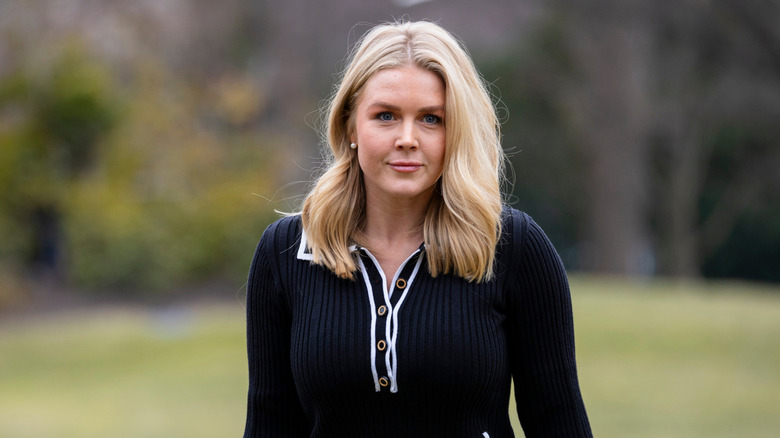 Karoline Leavitt walking outside in a black sweater with white trim