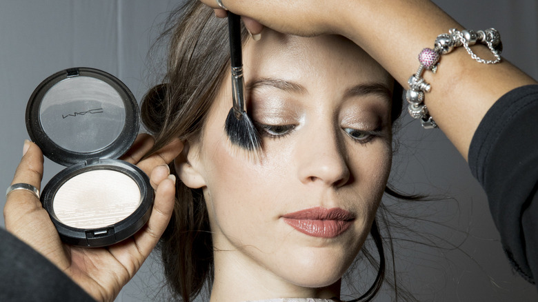 Makeup artist applies highlighter