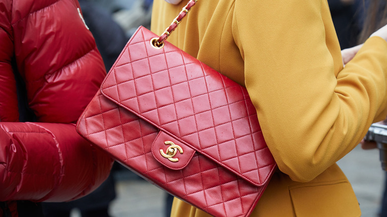 Red chanel bag over the shoulder of a woman wearing a yellow coat