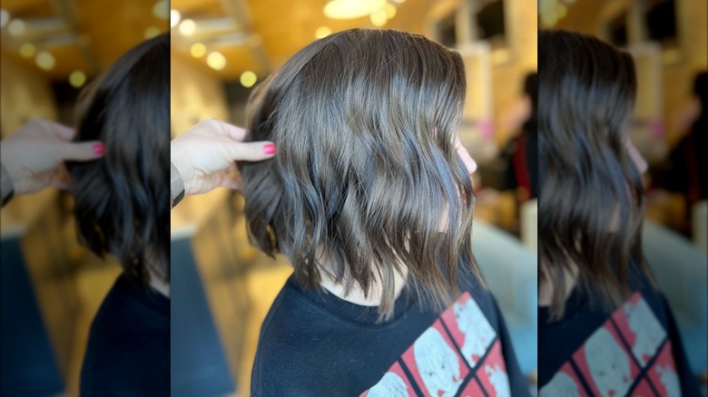 A side shot of a brunette woman with a bob haircut that's lightly curled