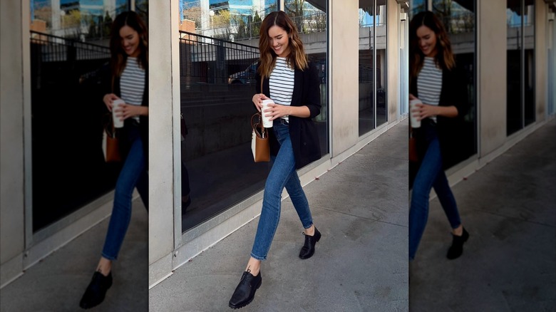 A woman wearing a striped shirt, skinny jeans, and a pair of black jazz shoes