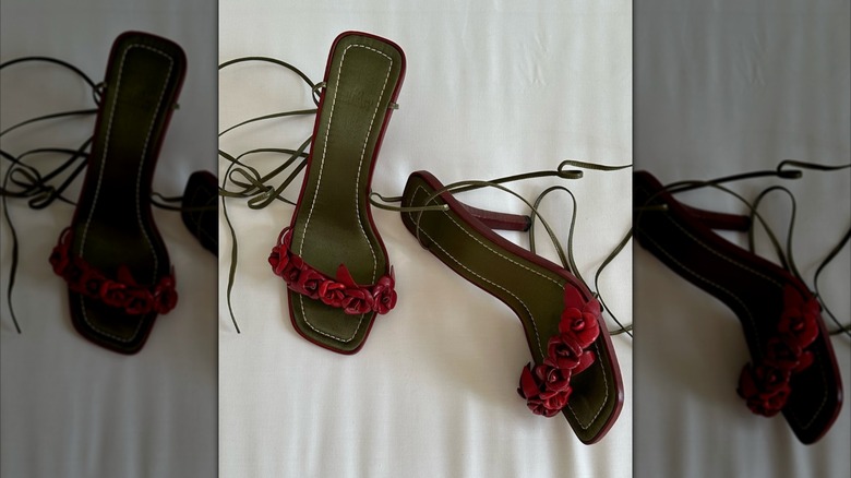 A pair of strapy sandals with rosettes on the toe bands laying on a white sheet