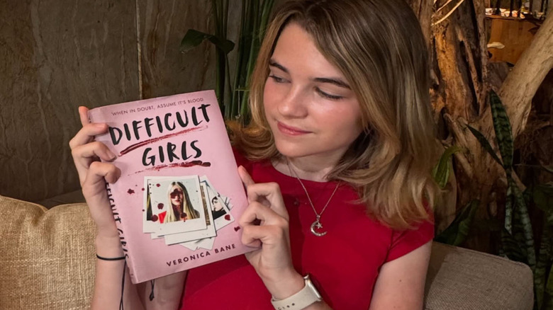 Raegan Revord holding up Difficult Girls book