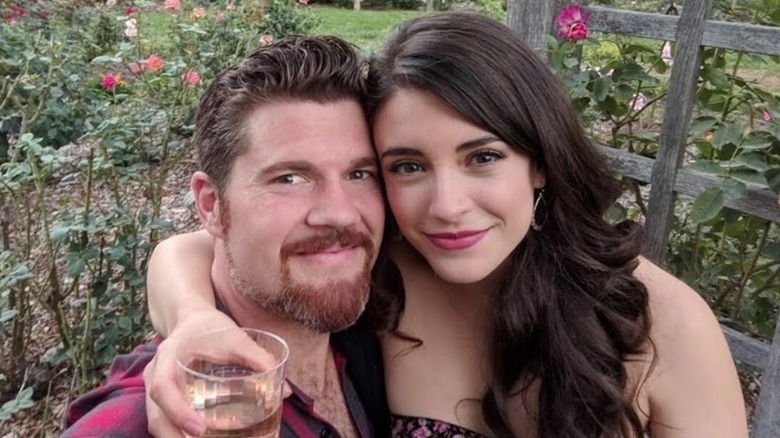 Daniela Bobadilla posing in a garden with Beau Wirick with holding a drink
