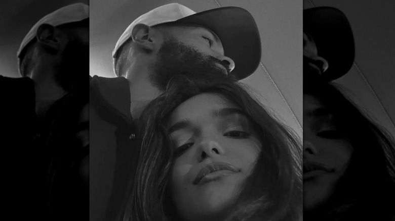 A black-and-white selfie of Rachel Zegler hugging Nathan Louis-Fernand