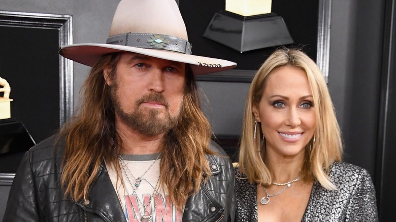 Billy Ray Cyrus and Tish Cyrus posing together on the red carpet in front of a black background