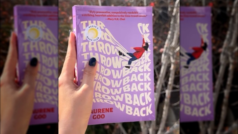 A person holding Throwback by Maurene Goo