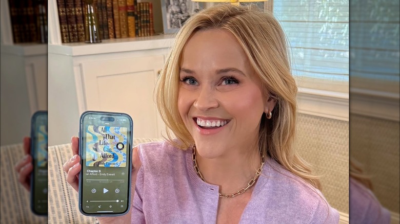 Reese Witherspoon holding up the audiobook version of All That Life Can Afford