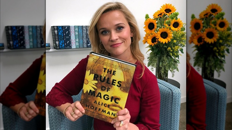 Reese Witerspoon holding a copy of The Rules of Magic