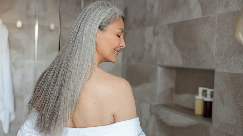 A woman taking off her bathrobe to prepare to shower in the bathroom