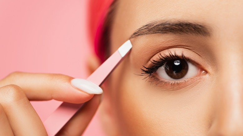 Closeup of woman tweezing eyebrows