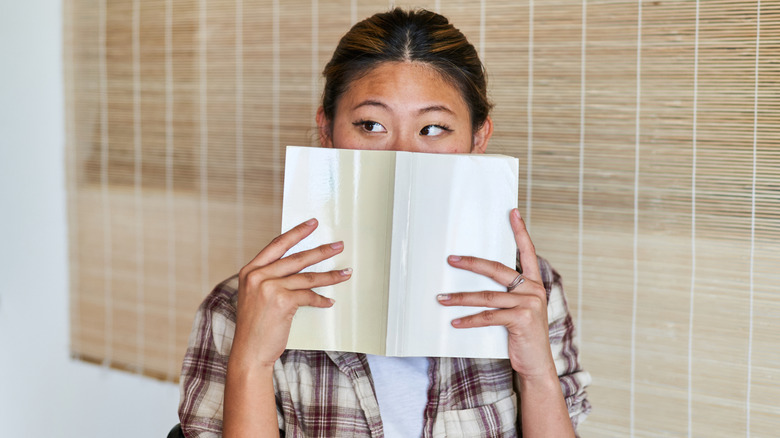 Woman hiding her face with a book
