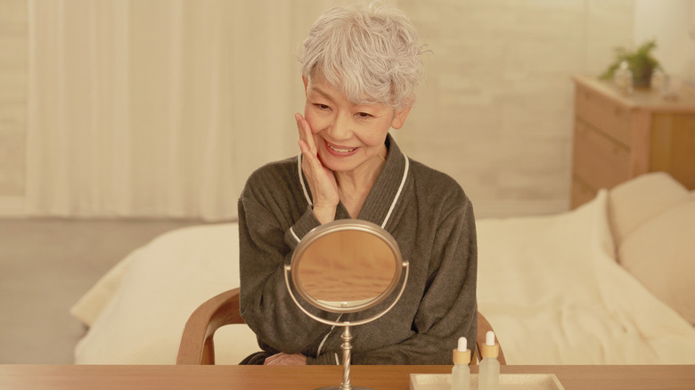 An older woman smiling as she looks in the mirror