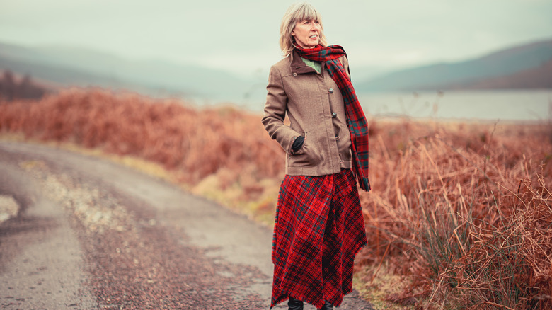 Older woman wearing a long plaid skirt in the countryside