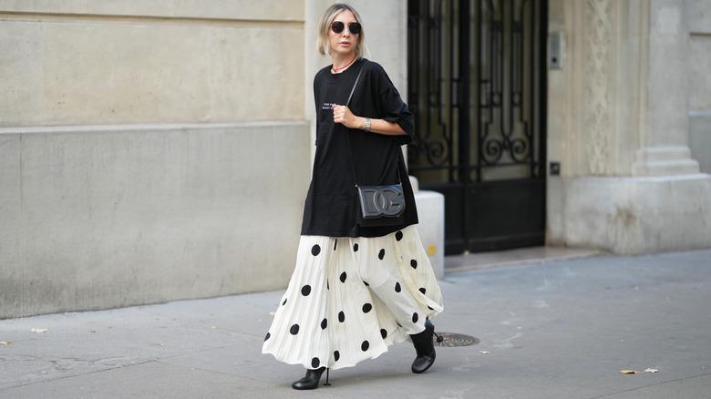 Woman walking in large black t-shirt and white maxi skirt with black polka dots