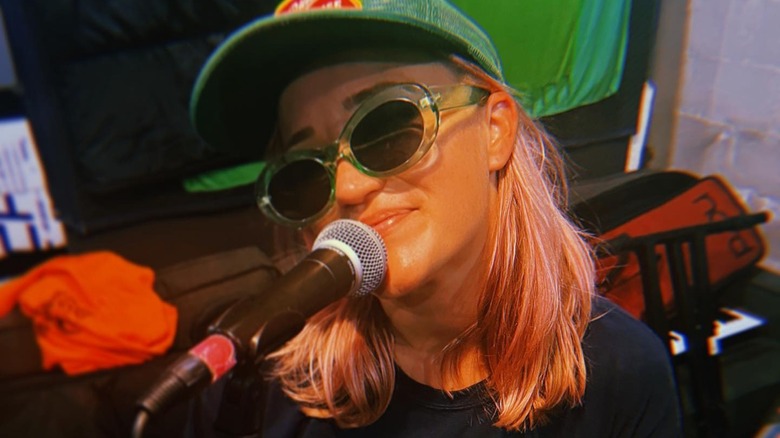 Emily Osment next to a microphone with pink hair