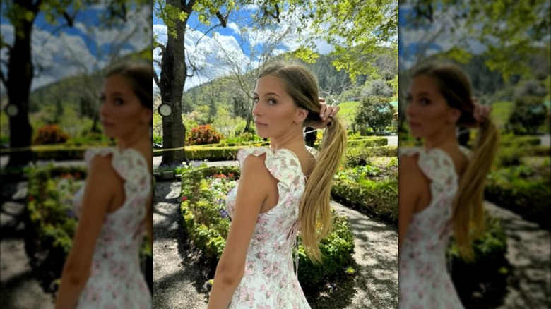 Romy Mars standing in a garden and playing with her hair