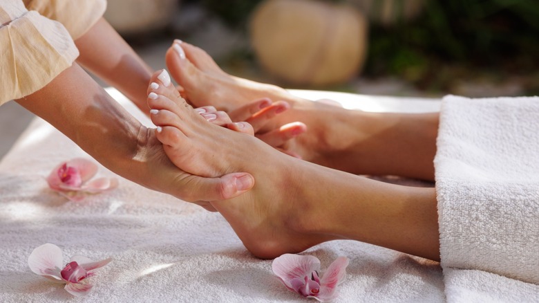 A person laying under a towel and getting a treatment on their pedicured feet