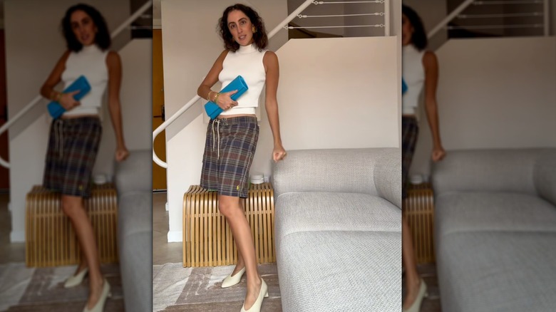 A woman on TikTok styling board shorts with a blue clutch and white heels