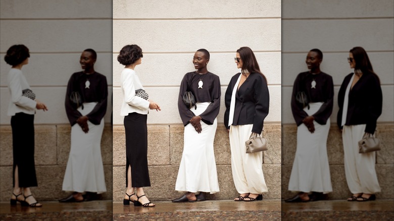 A group of three women standing on the street wearing black and white minimalistic fashion styles