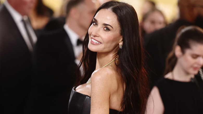 Demi Moore smiling over her shoulder at a 2025 red carpet event