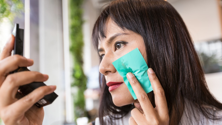 A woman using an oil blotter 