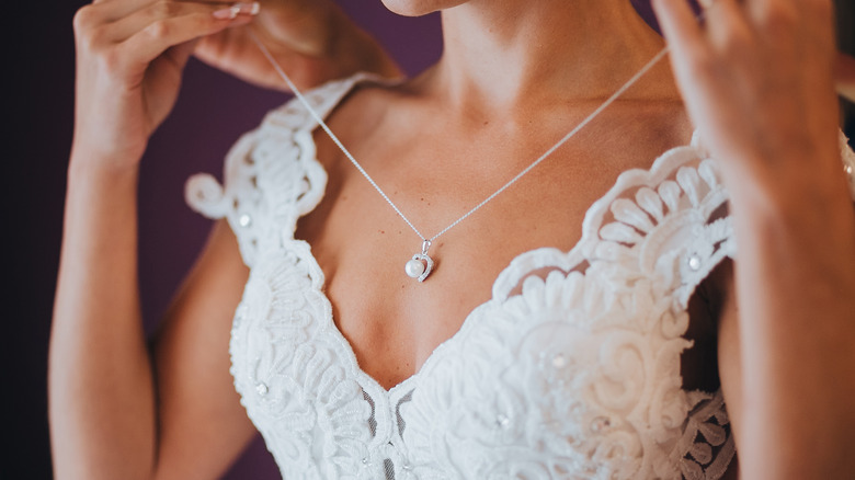 Bride putting on necklace