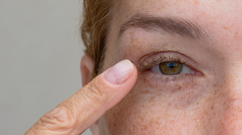 A finger pointed at a hooded hazel eye