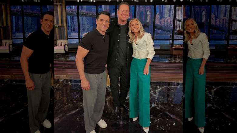 Kelly Ripa posing with Mark Consuelos and Brendan Fraser while wearing a striped button-up and trousers