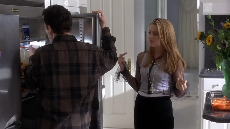 A scene from Clueless with Cher in a black sheer top talking to a man opening the fridge