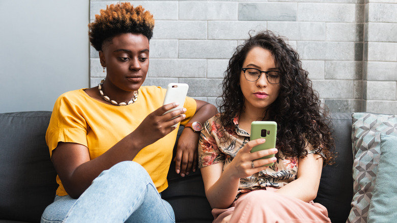 two people texting on couch