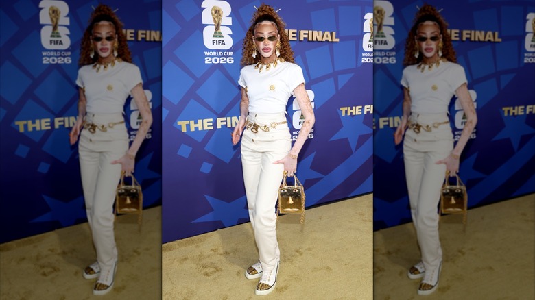 Winnie Harlow wearing a gold waist belt with a white outfit on the red carpet at the World Cup