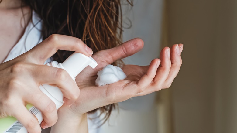 Woman applying hair mousse