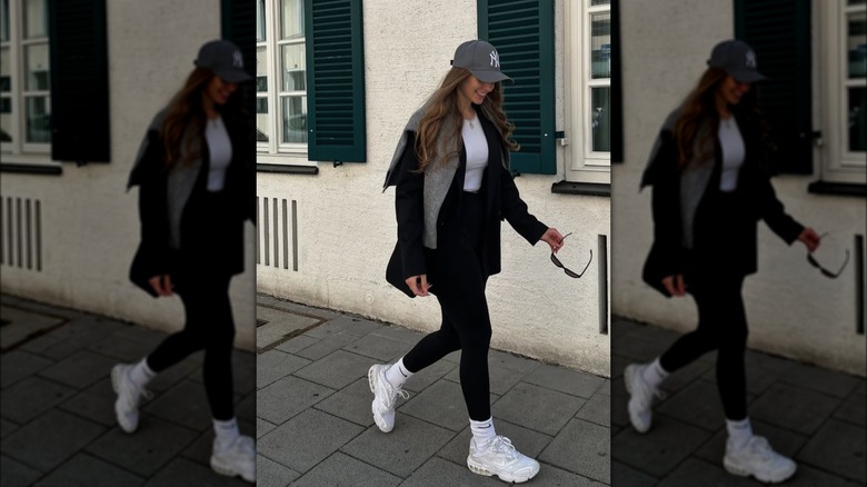 A woman in leggings with a grey baseball cap and a grey cardigan