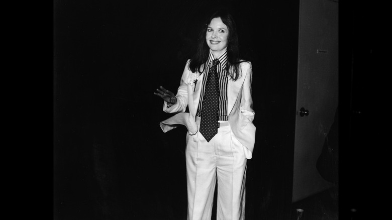A black-and-white photo of Diane Keaton posing at the 1976 Oscars in a white suit