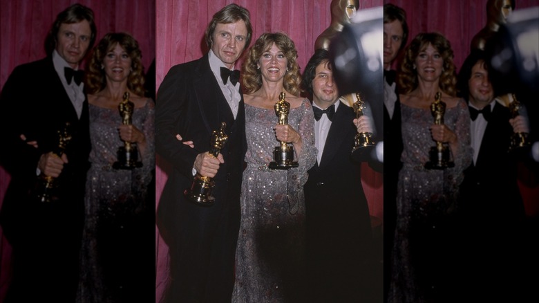Jane Fonda smiling and holding her Oscar alongside Michael Cimino and Jon Voight