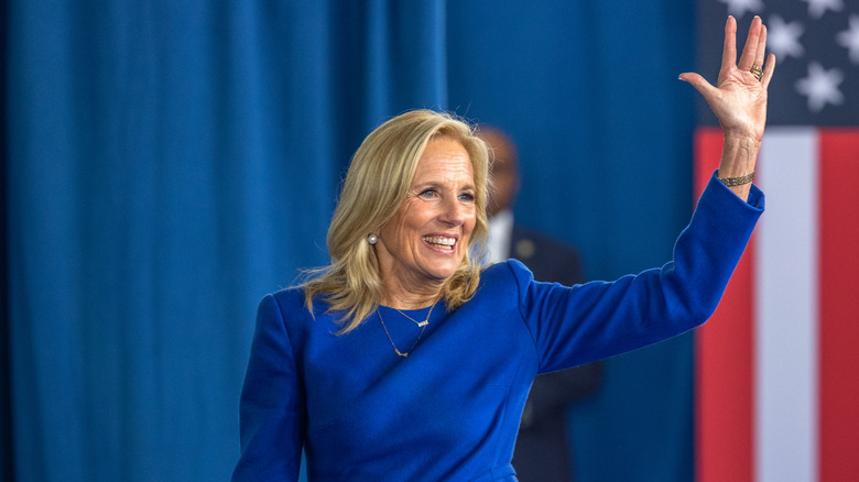 Jill Biden smiles and waves wearing a blue dress