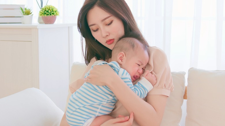 Pensive mom holding a baby 