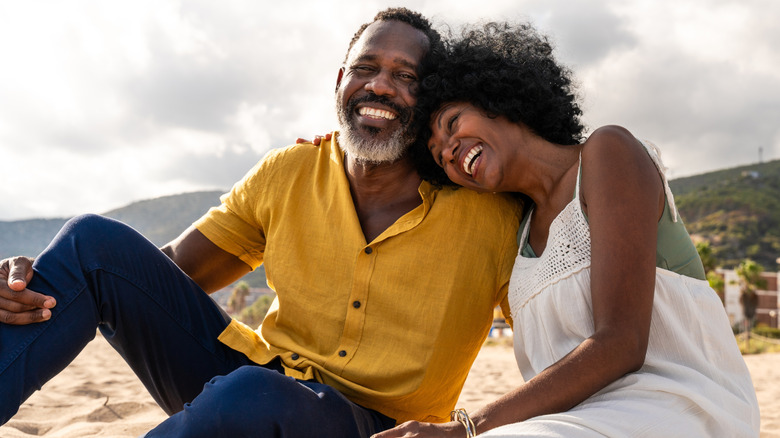 older woman and man in laughing on the beach