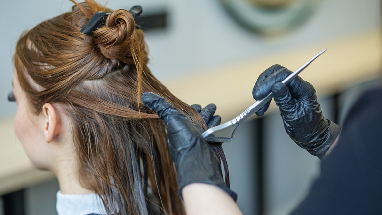 Hairdresser applies hair color to client