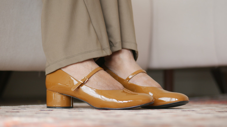 Close-up of caramel-colored Mary Janes worn with biege slacks